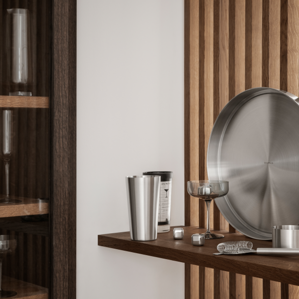 Moderne Küchenbar mit Edelstahlwerkzeugen und eleganten Gläsern auf Holzregalen.
