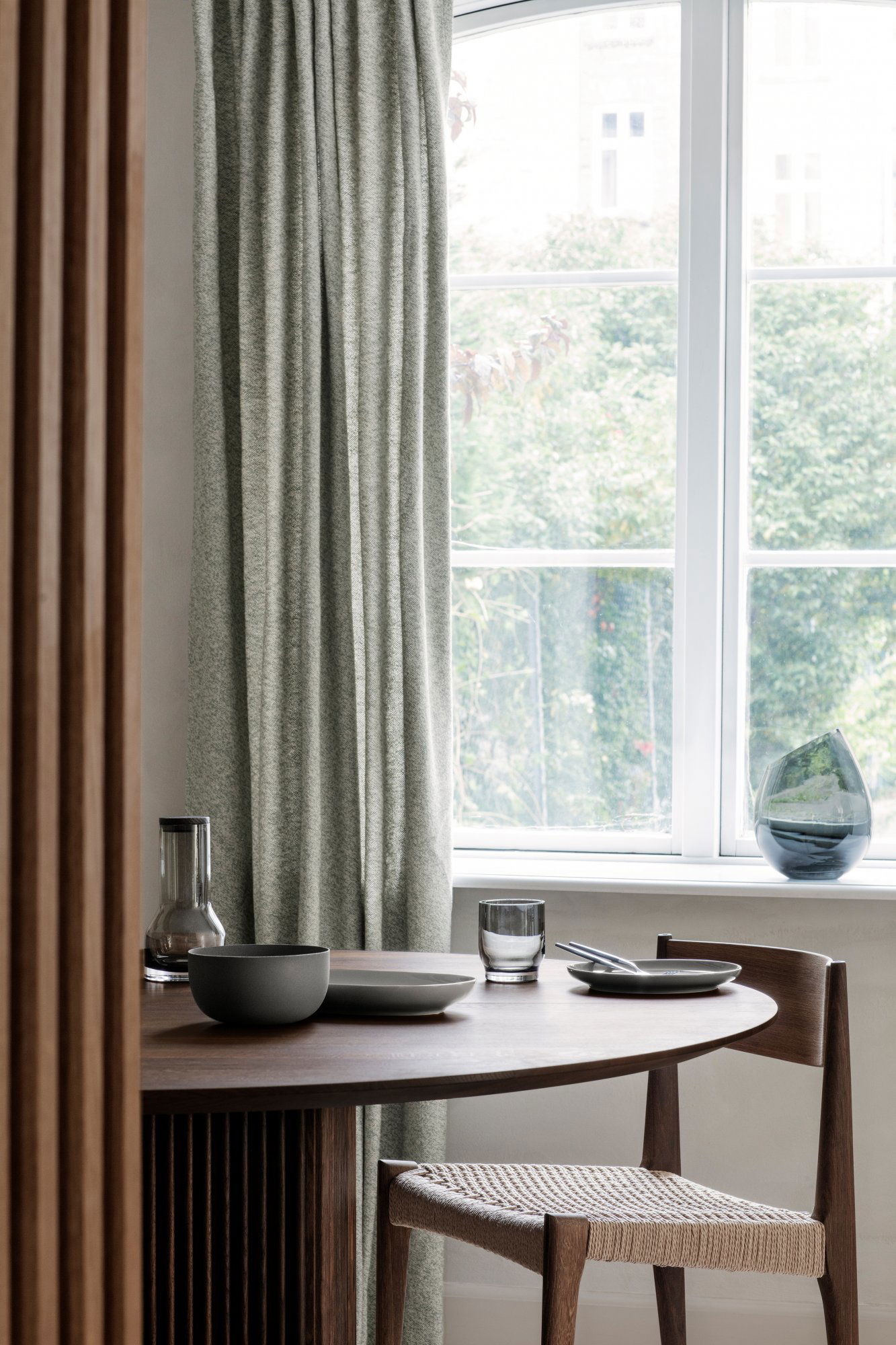 Cozy dining setup with modern tableware by a window with green views.