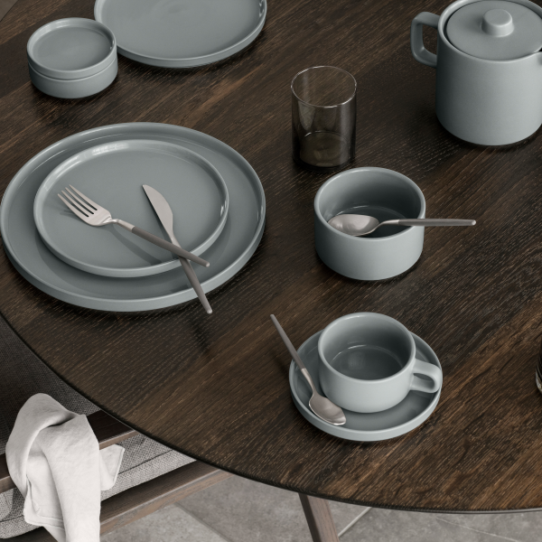 Stilvolles graues Geschirrset auf einem Holztisch für elegante Mahlzeiten angeordnet.