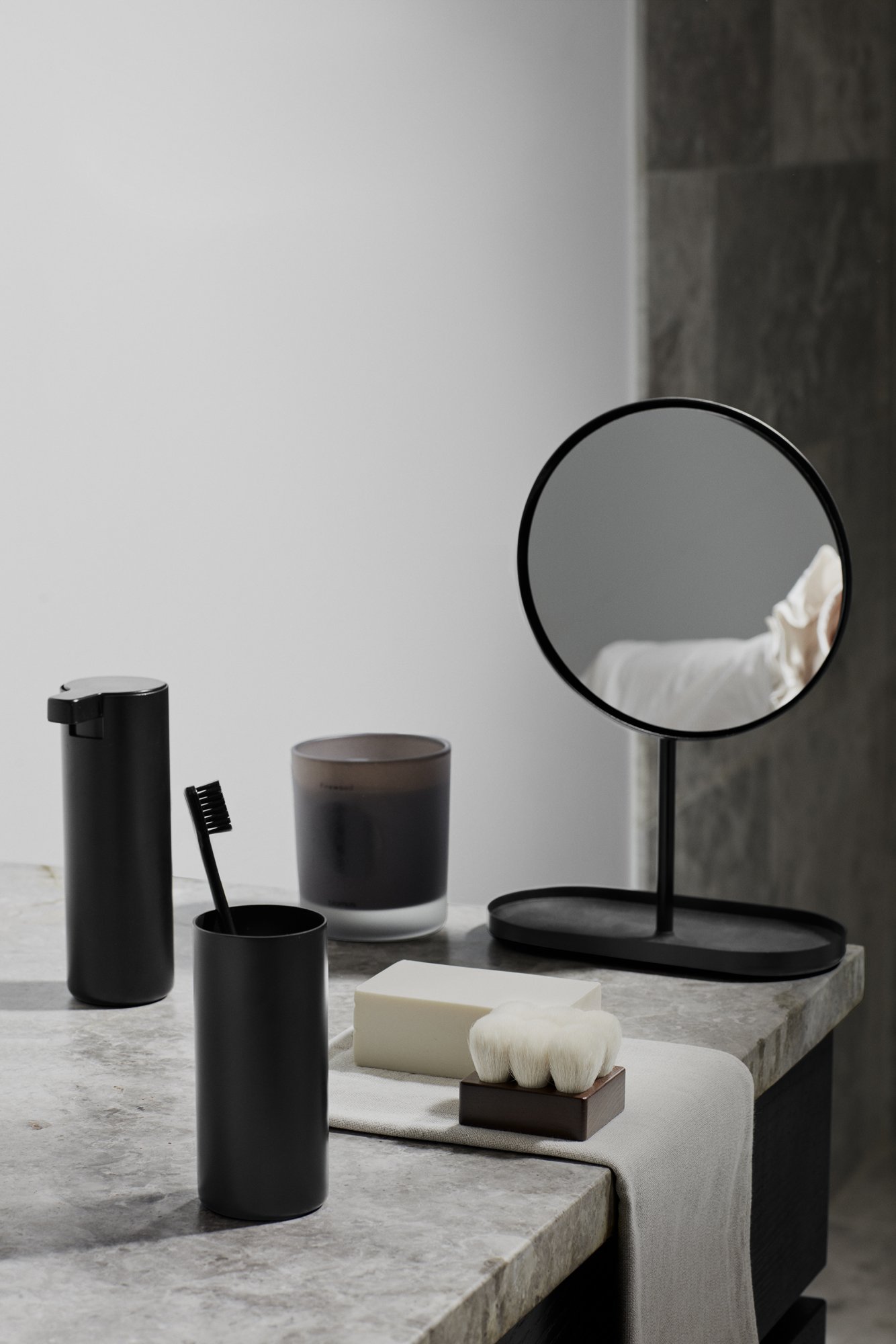 Moderne Badezimmer-Einrichtung mit schwarzen Accessoires und einem runden Spiegel.