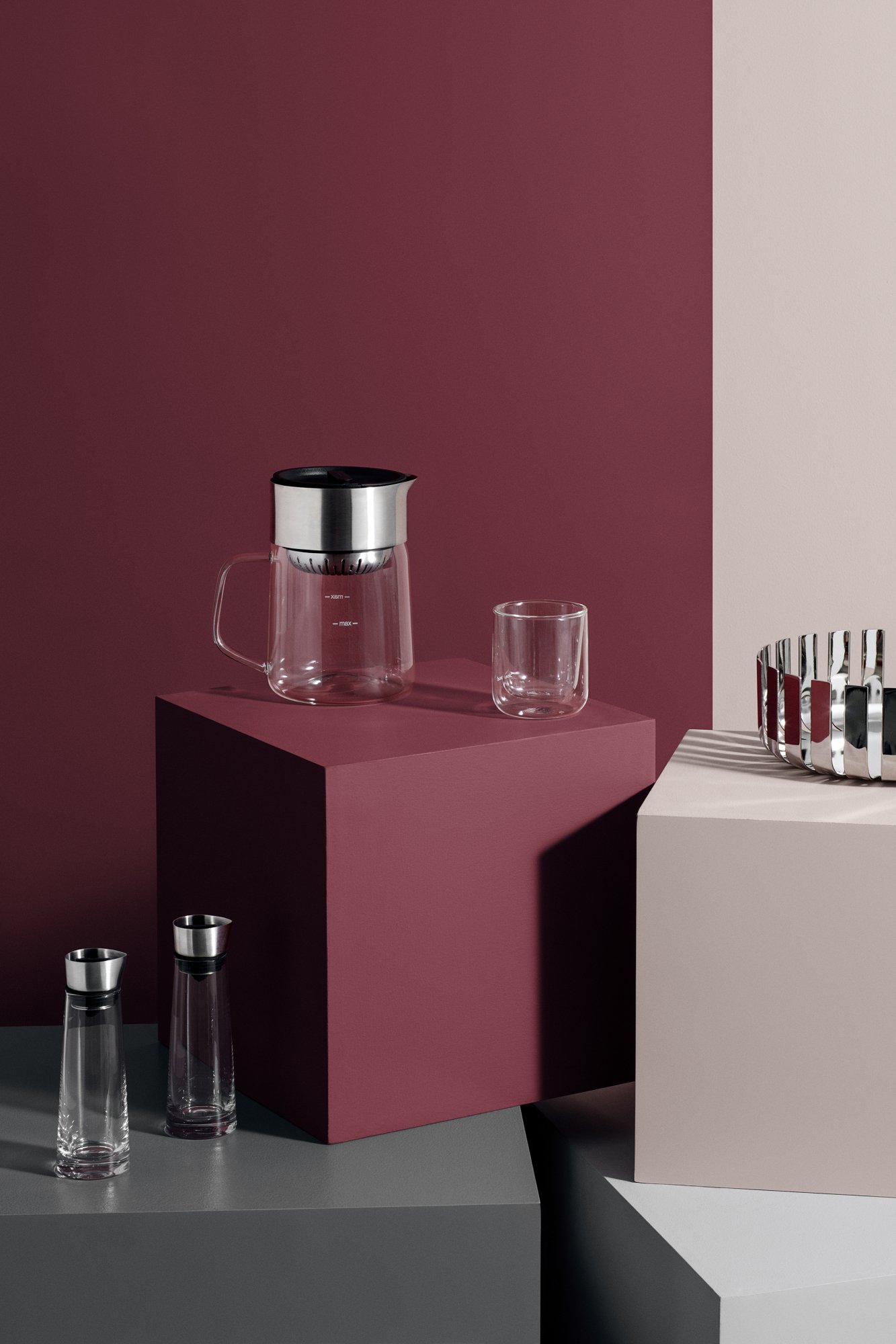 Moderne Glas-Kaffeemaschine und Tasse auf minimalistischem, farblich abgesetztem Display.