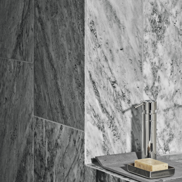 Sleek modern bathroom with marble walls and stylish soap dispenser on a countertop.