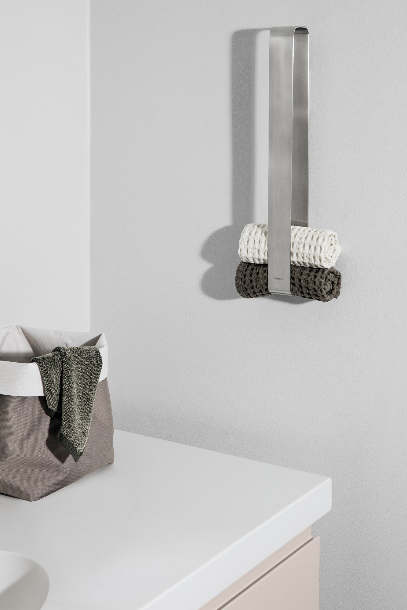 Modernes Badezimmer mit ordentlich gerollten Handtüchern und einem stilvollen Aufbewahrungskorb.