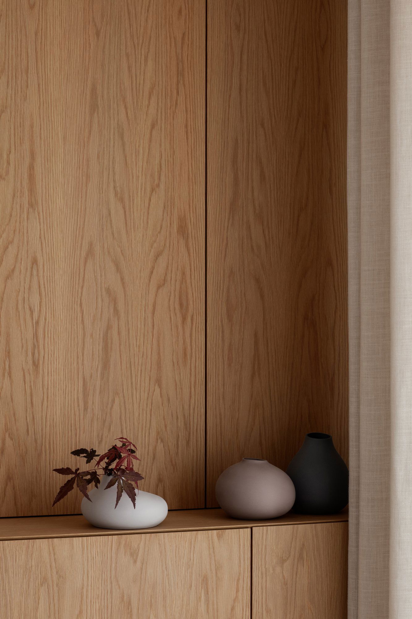 Stilvolles Interieur mit Holzverkleidung und minimalistischen Vasen mit dekorativem Laub.