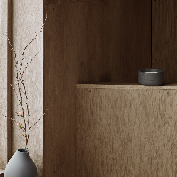 Minimalistische Einrichtung mit Holzregalen und einer einfachen Vase mit Zweigen.