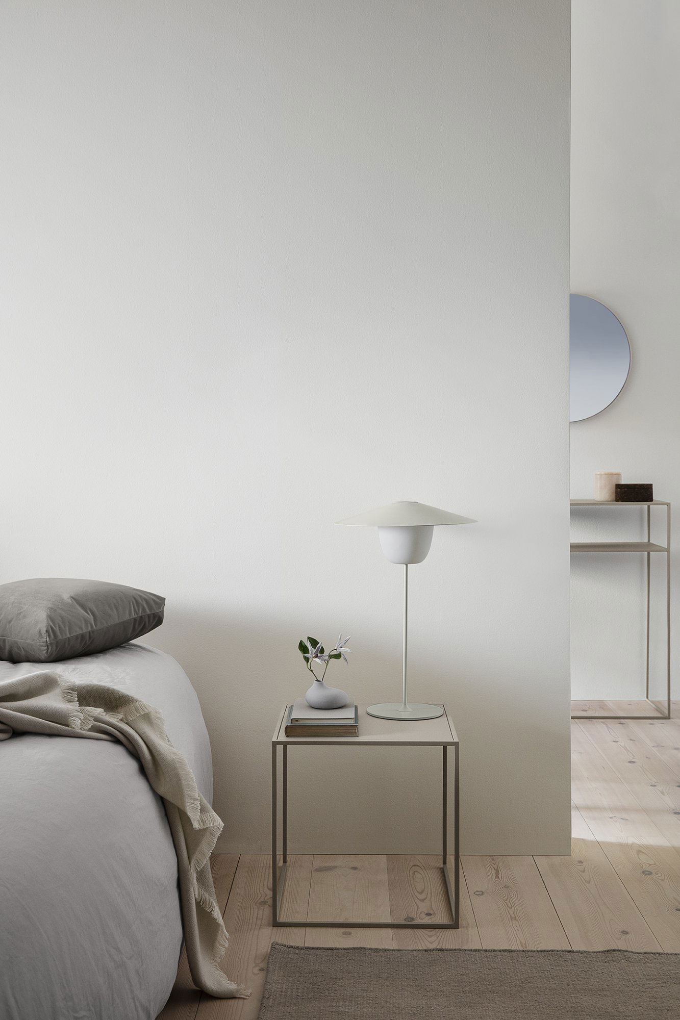 Minimalist bedroom with a gray bed, modern lamp, and simple decor for a calming atmosphere.