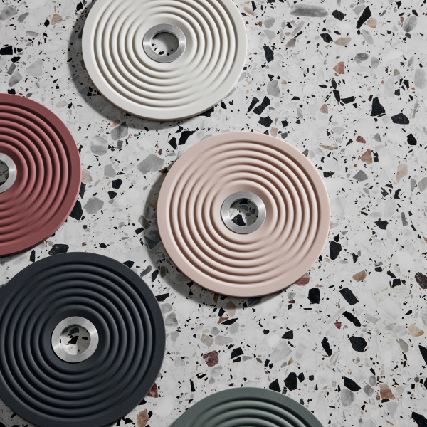 Bunte runde Untersetzer mit strukturierten Designs, die auf einer Terrazzo-Oberfläche angeordnet sind.