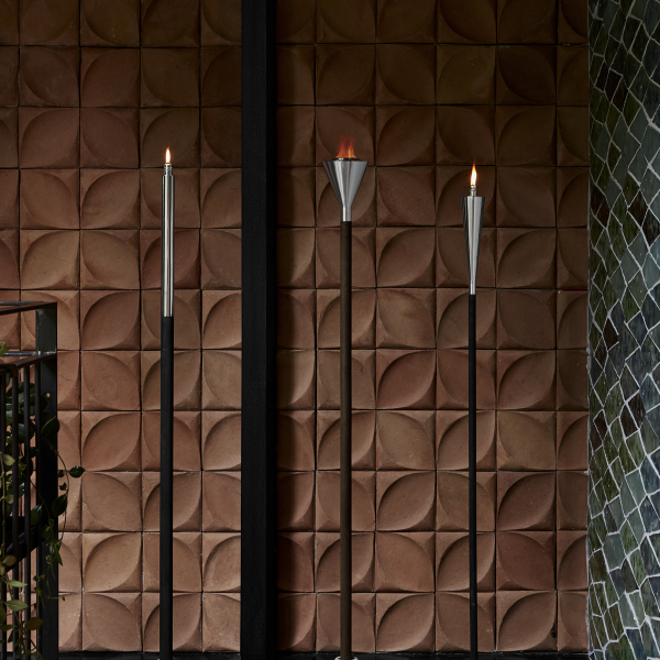 Stylische Wand mit strukturierten Fliesen und eleganten Wandleuchten im Fackelstil.