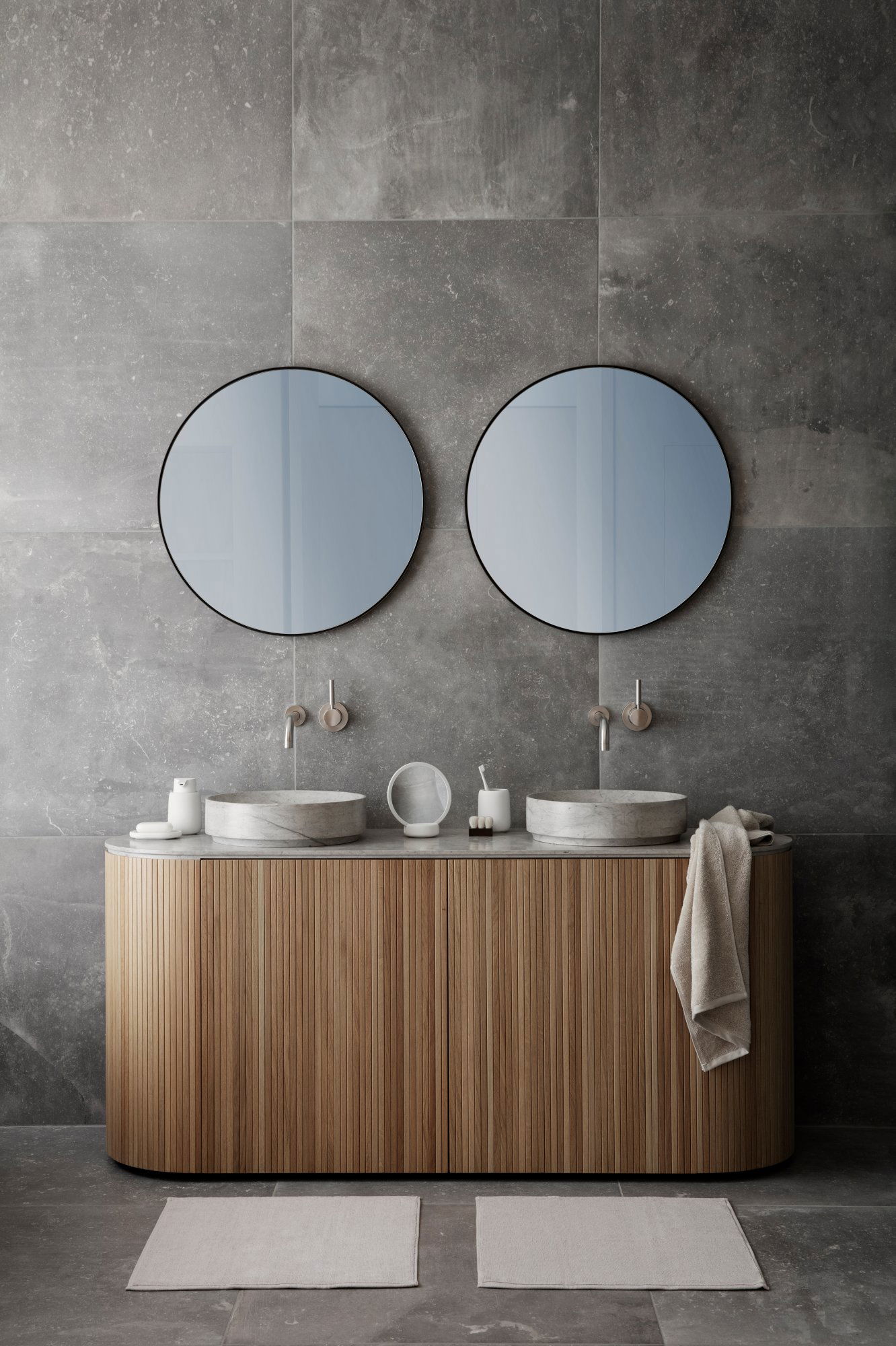 Moderne Badezimmergestaltung mit doppelten runden Spiegeln über einem Holzwaschtisch mit Waschbecken.