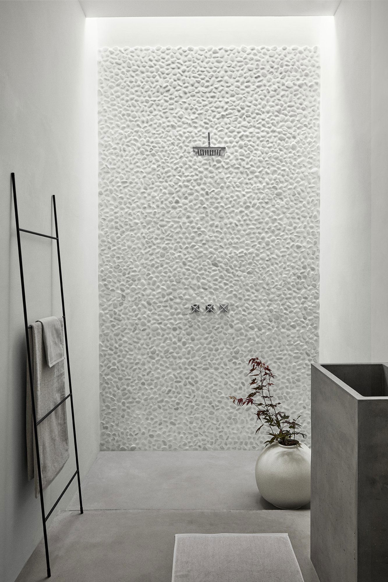 Moderne Dusche mit Kieselmauer, eleganten Armaturen und minimalistischer Dekoration in einem stilvollen Badezimmer.