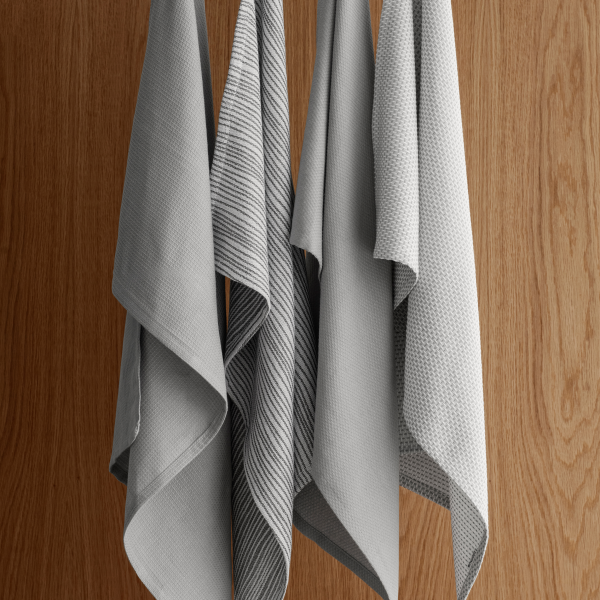 Soft gray kitchen towels elegantly hanging against a warm wooden background.