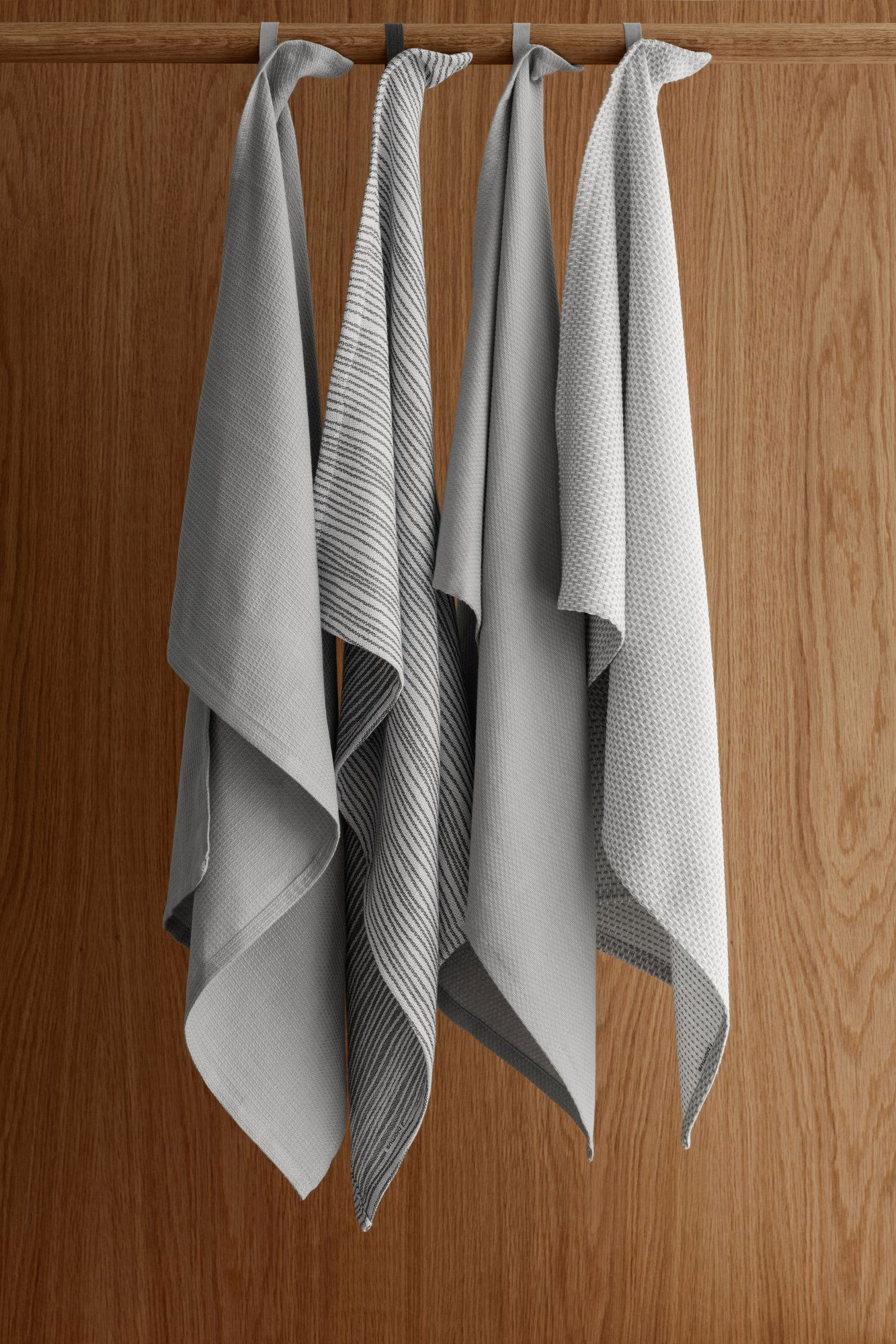 Soft gray kitchen towels elegantly hanging against a warm wooden background.