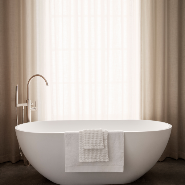 Modern bathroom featuring a sleek freestanding tub with a white towel draped over it.