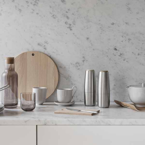 Modern kitchenware display with glass, stainless steel, and wooden elements on marble countertop.