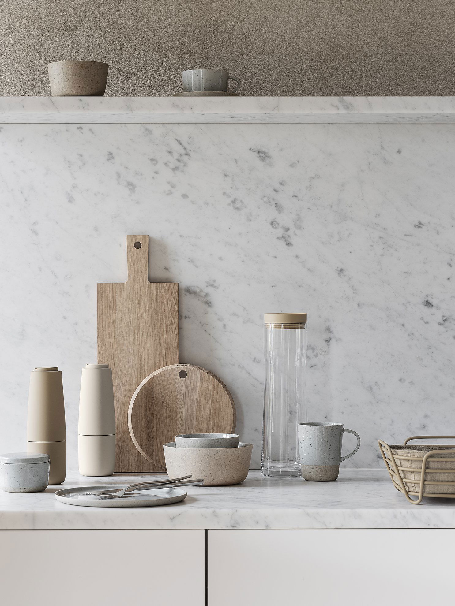 Minimalistische Küchenszene mit Holzservierbrettern, Keramiktellern und Glaswaren auf Marmor.