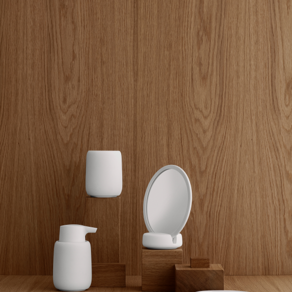 Minimalistische Badaccessoires auf einer Holzoberfläche vor einem strukturierten Hintergrund präsentiert.
