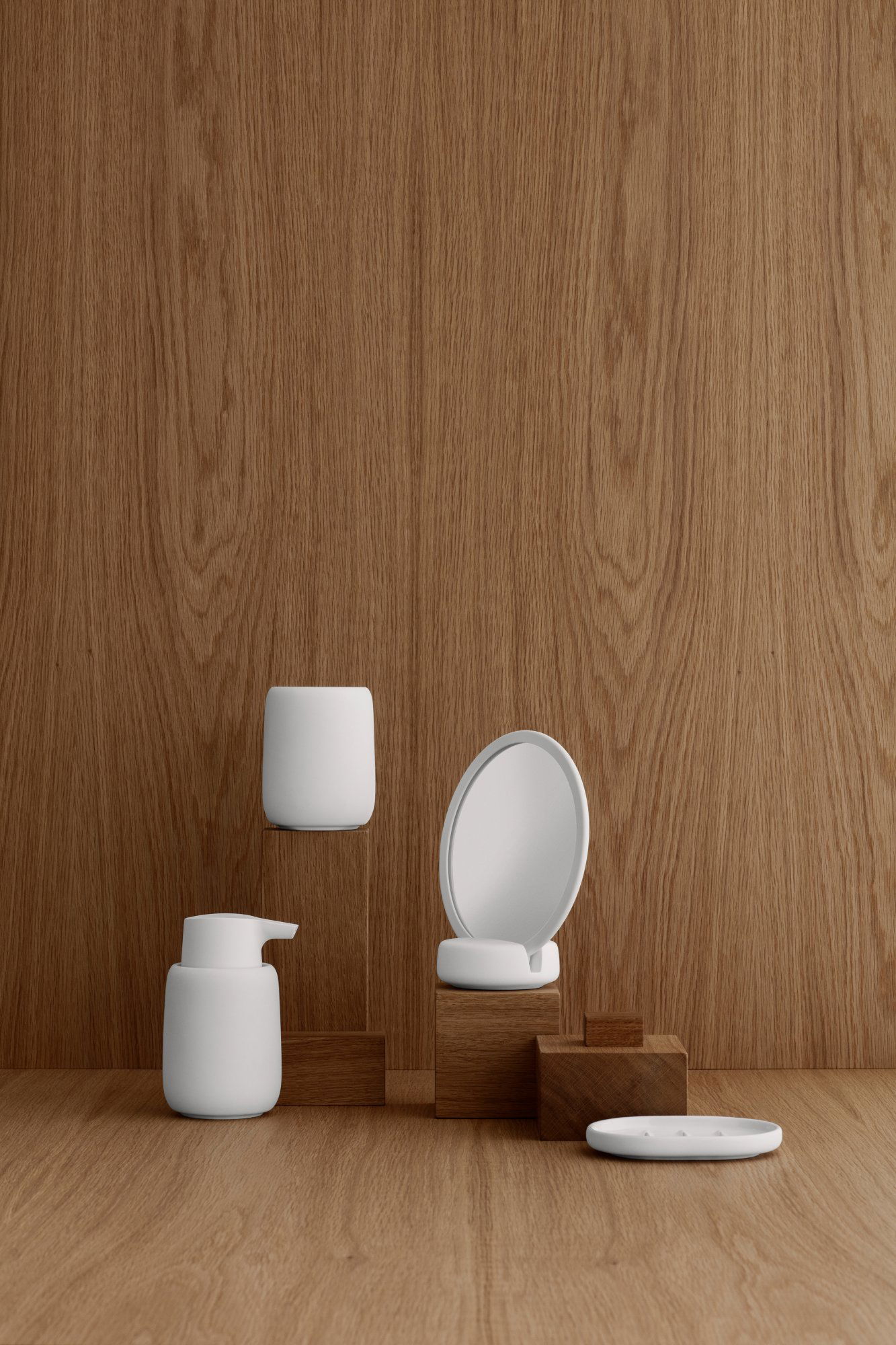 Minimalistische Badaccessoires auf einer Holzoberfläche vor einem strukturierten Hintergrund präsentiert.