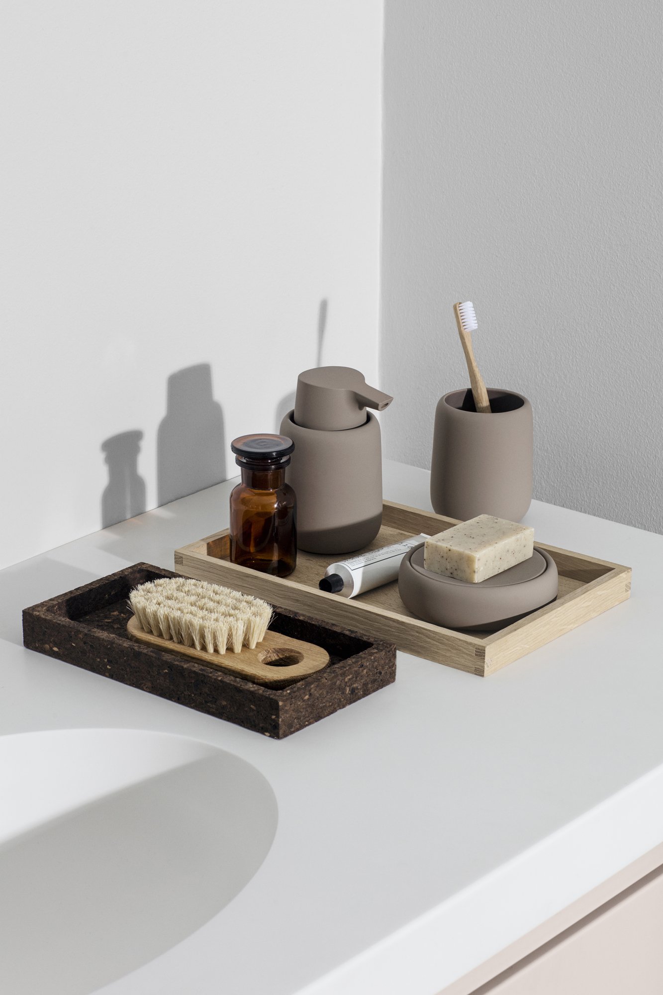 Minimalistische Badezimmeraccessoires auf einem Holztablett angeordnet, mit natürlichen Materialien und sanften Farben.