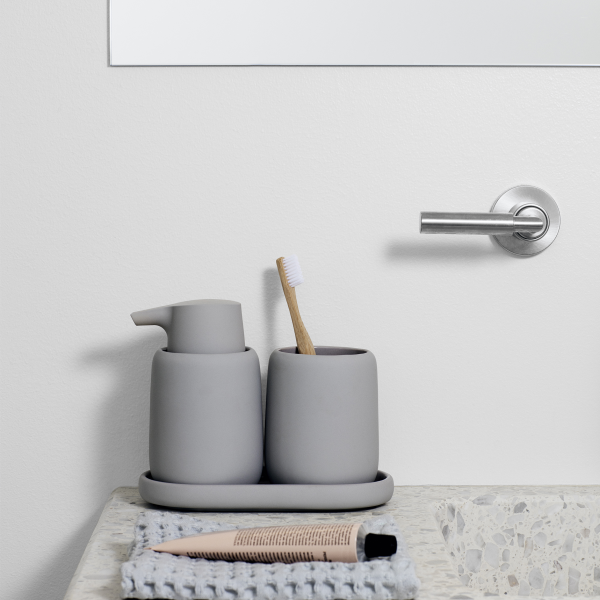 Elegante Badezimmerarbeitsplatte mit grauen Accessoires und einer Zahnbürste in einem minimalistischen Ambiente.