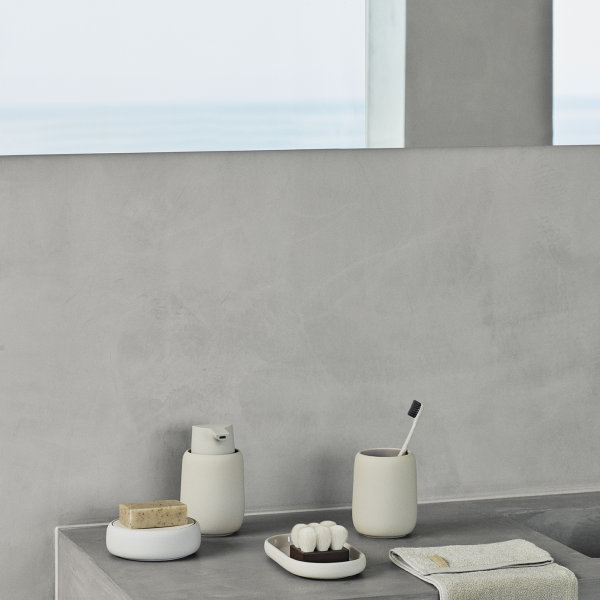 Minimalistische Badezimmerdekoration mit grauen Oberflächen und eleganten Accessoires am Fenster.
