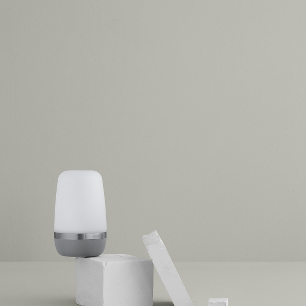 Minimalistische Nachttischlampe auf einem hellgrauen Hintergrund mit weißen Blöcken.