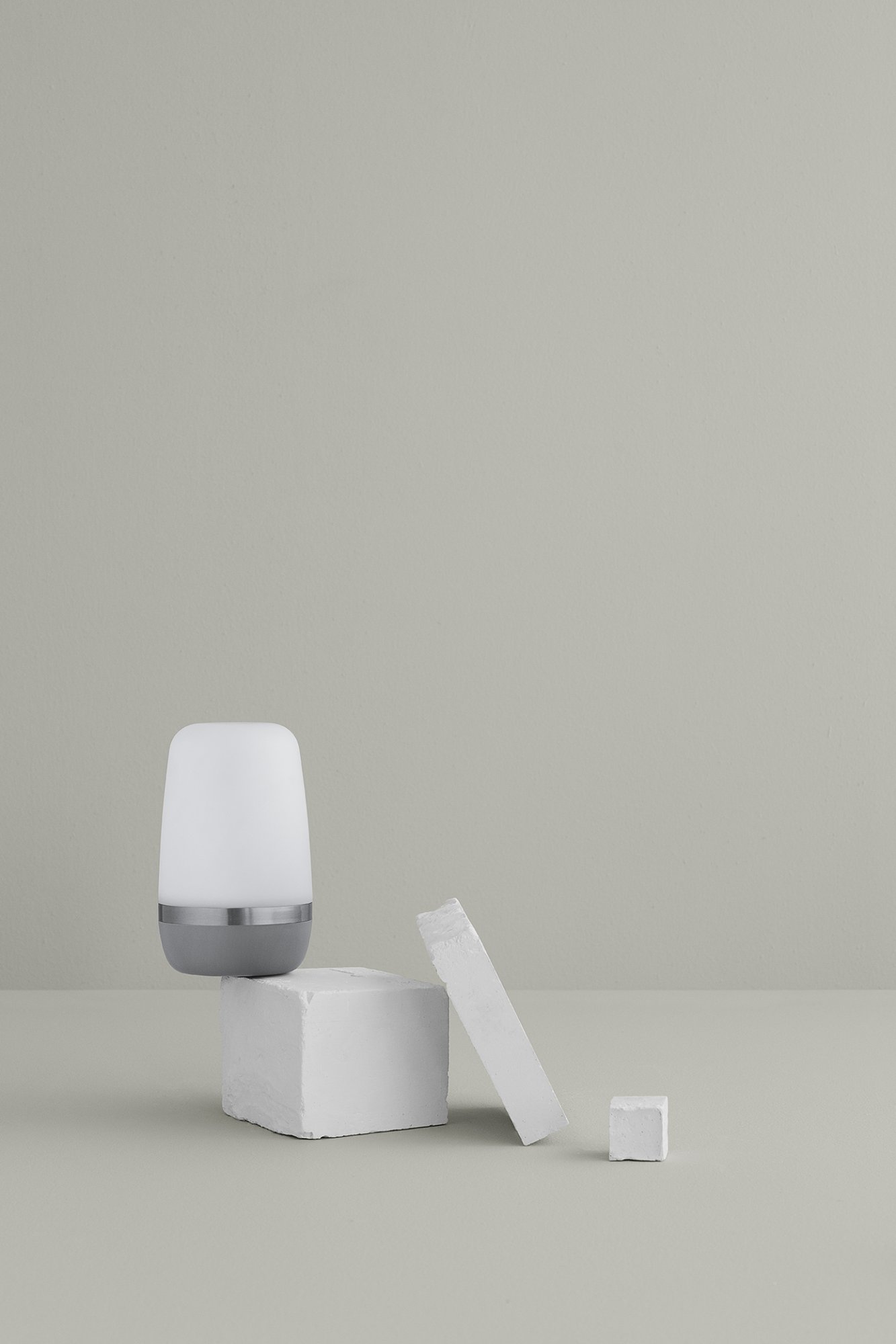 Minimalistische Nachttischlampe auf einem hellgrauen Hintergrund mit weißen Blöcken.