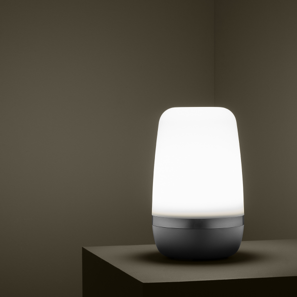 Modern lamp with a sleek design illuminating a minimalist room corner.