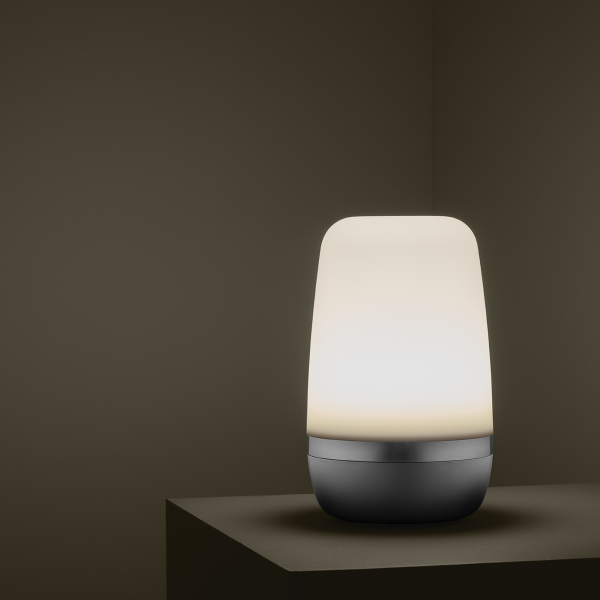 Modern table lamp with a soft glow against a minimalistic dark background.