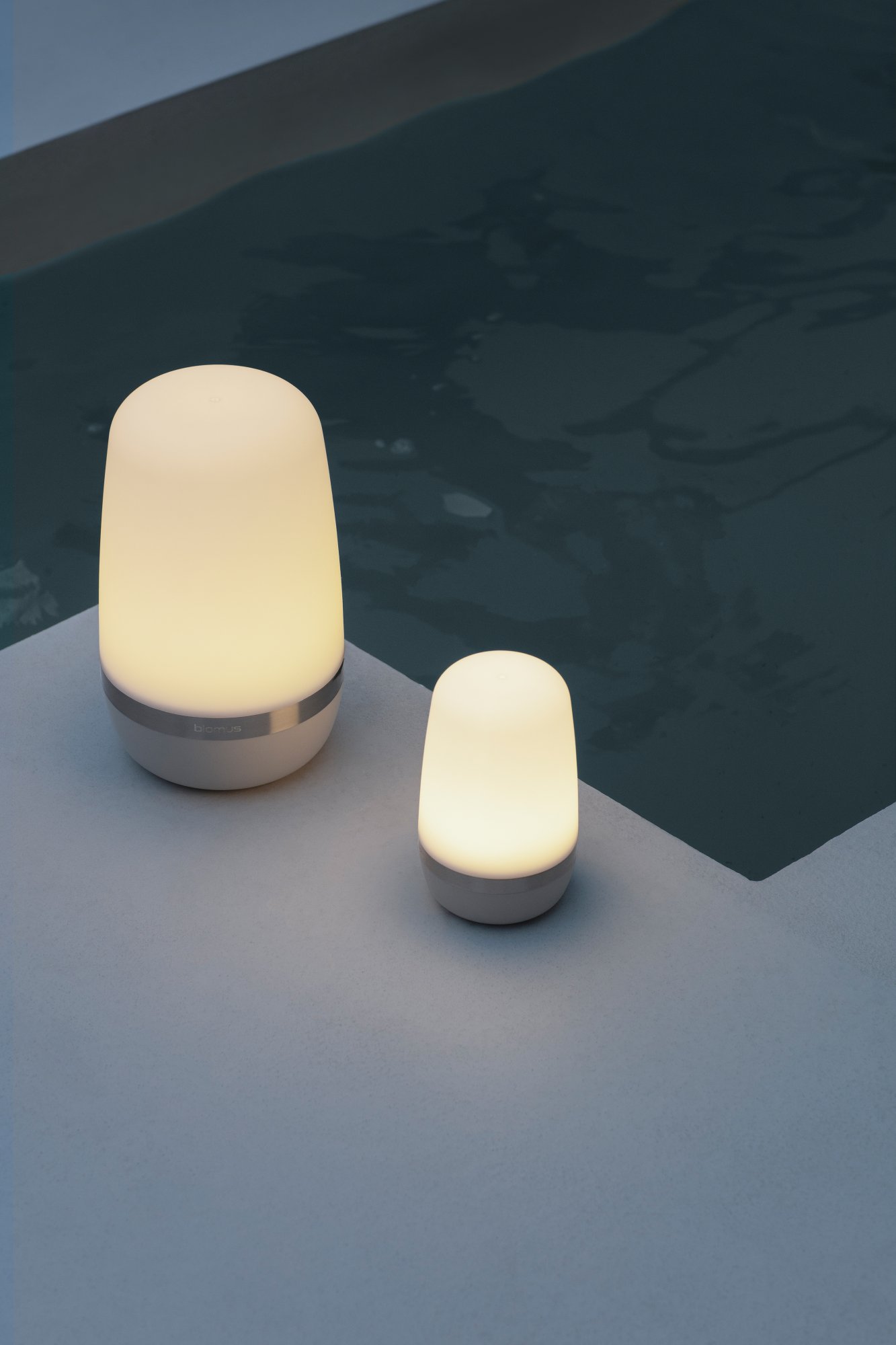 Soft glow of stylish outdoor lamps by a pool at night.