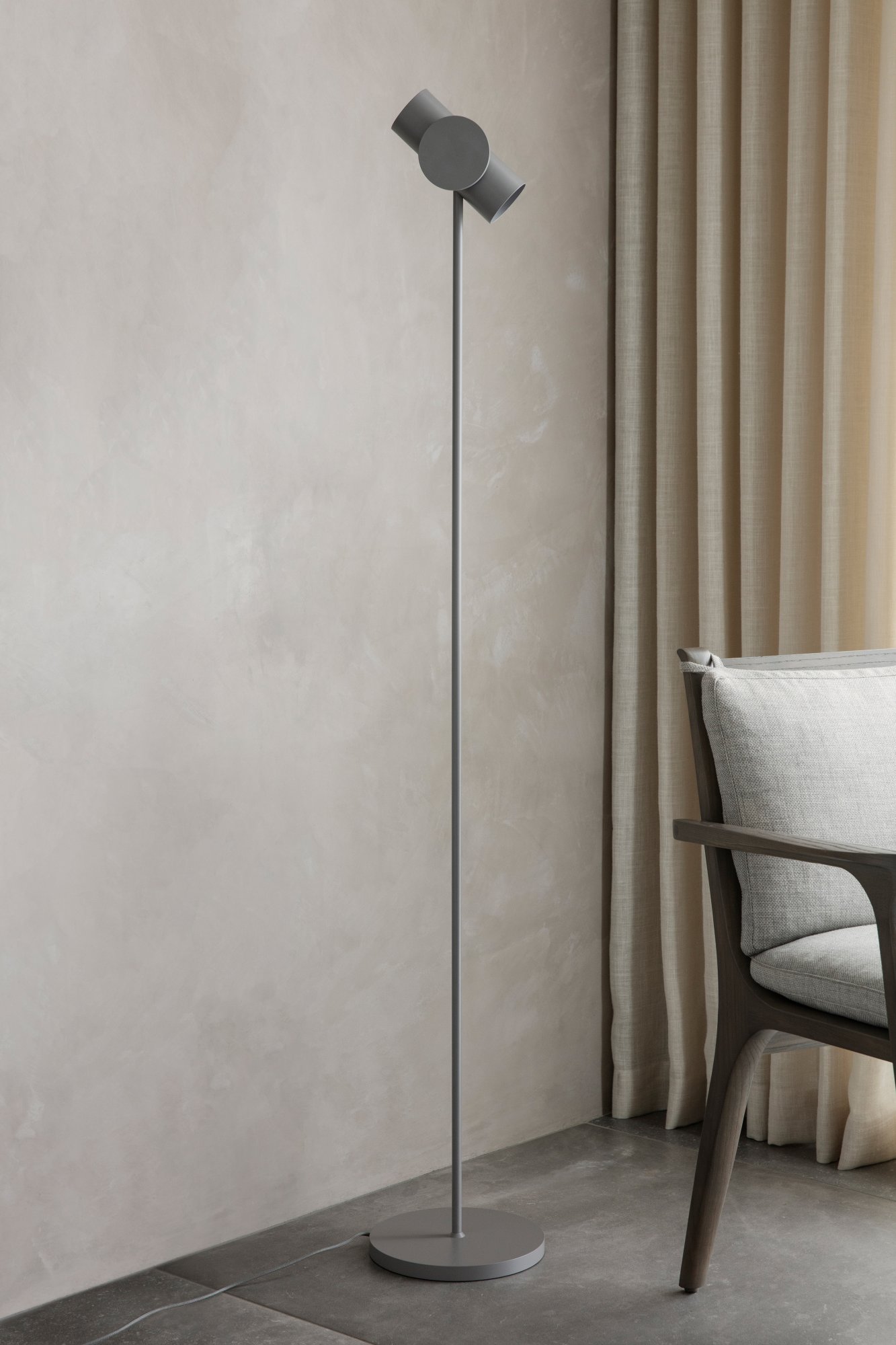 Modernes Interieur mit einem stilvollen Stuhl neben einer strukturierten Wand und weichen Vorhängen.