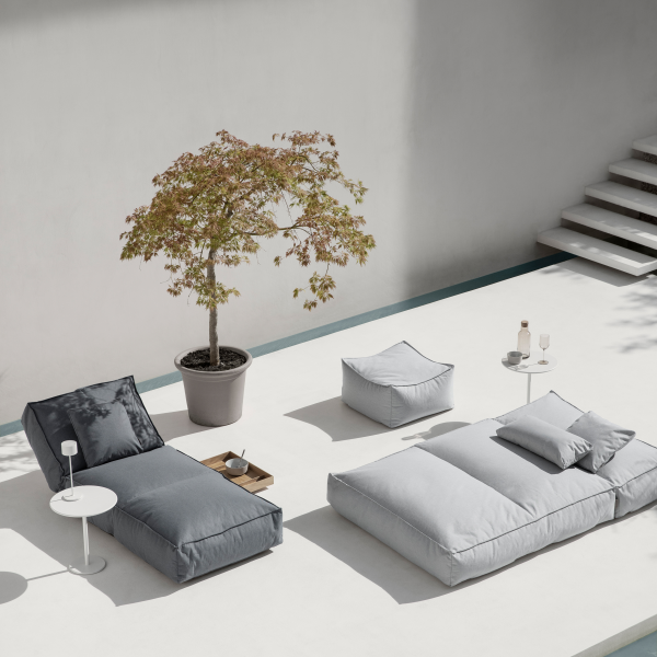 Stylish outdoor lounge area with modern cushions and a decorative tree in a serene setting.