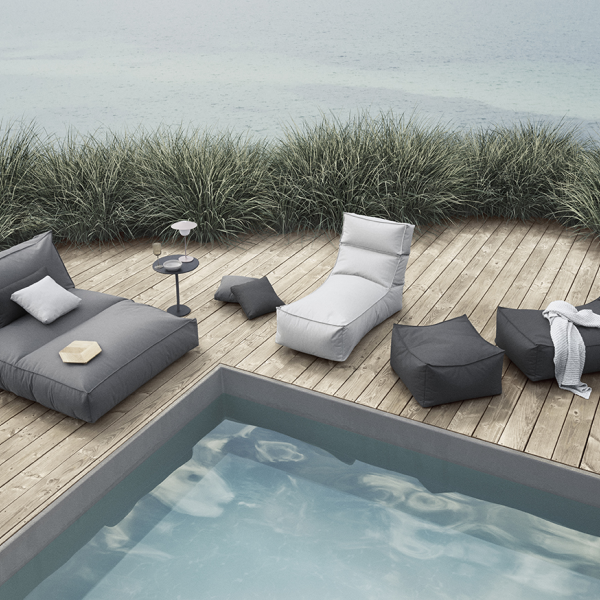 Stylischer Außenlounge-Bereich am Pool mit modernen Möbeln und sanfter Begrünung.
