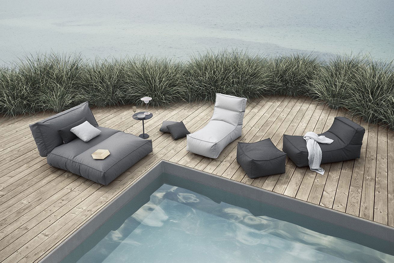 Stylischer Außenlounge-Bereich am Pool mit modernen Möbeln und sanfter Begrünung.
