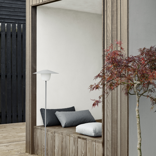 Cozy outdoor seating area with modern lamp and decorative maple tree.
