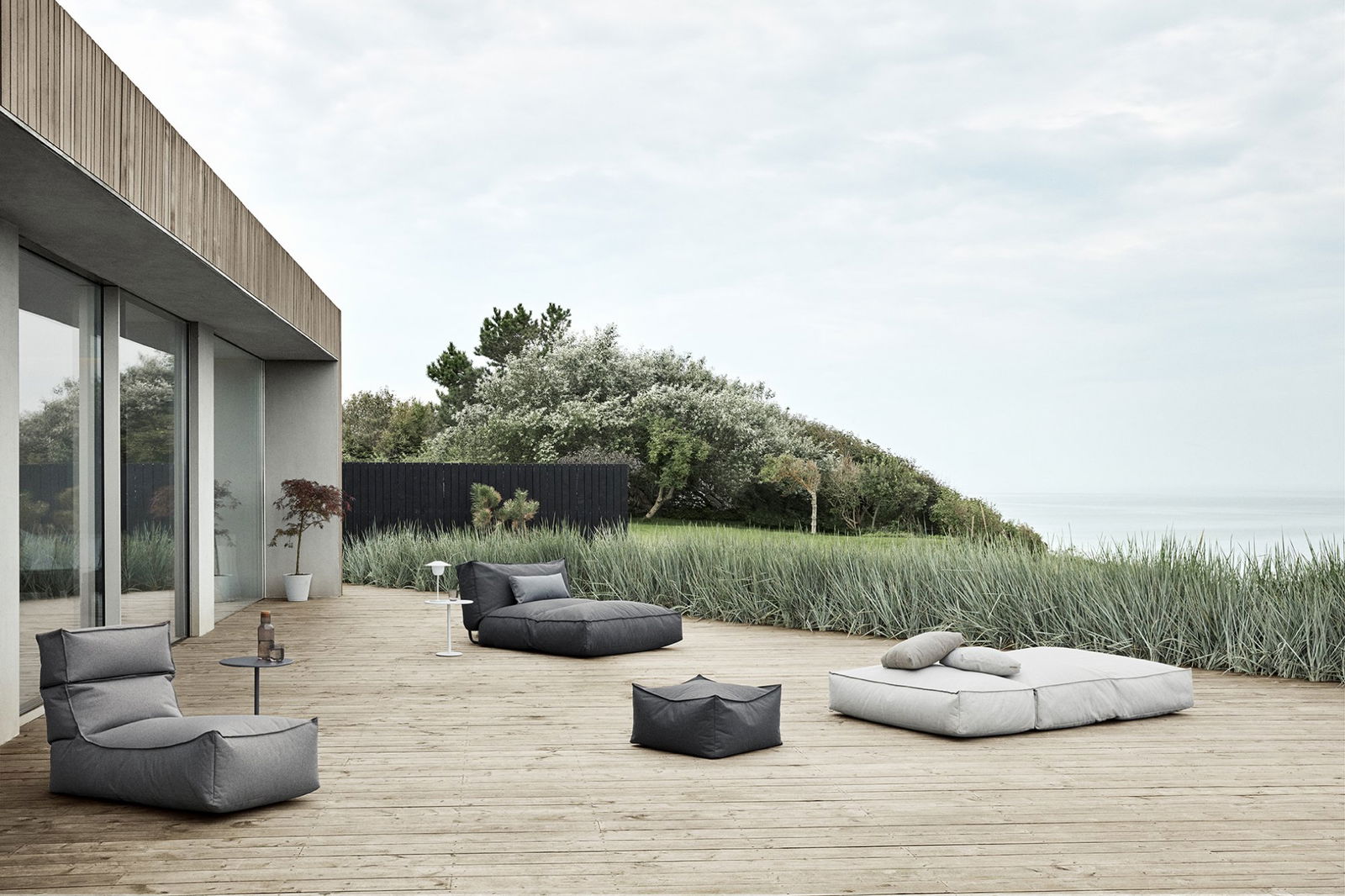 Moderner Außenbereich mit stilvollen Sitzsäcken und üppigem Grün am Meer.