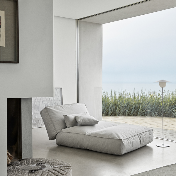 Modern minimalist living room with a plush lounge chair and scenic ocean view.