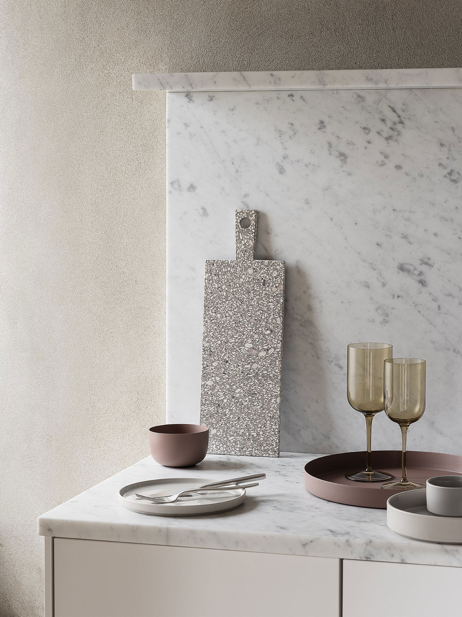 Elegante Küchenszene mit Terrazzo-Schneidebrett, Glaswaren und minimalistischen Geschirr.
