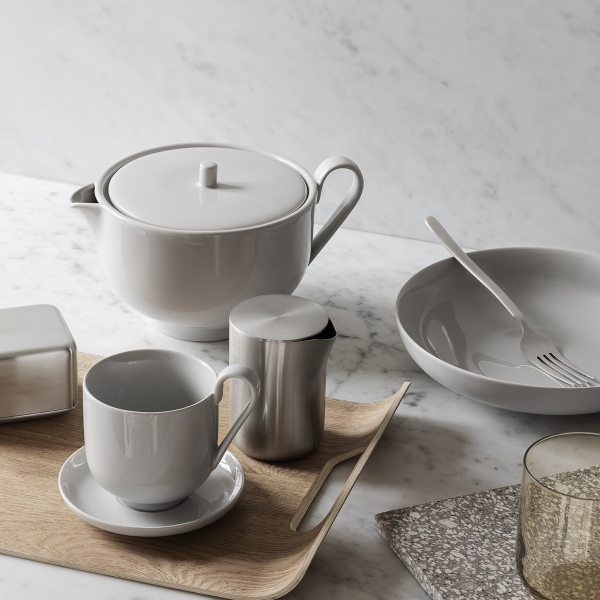 Elegant gray ceramic tea set with a wooden tray and minimalist dinnerware on a marble surface.