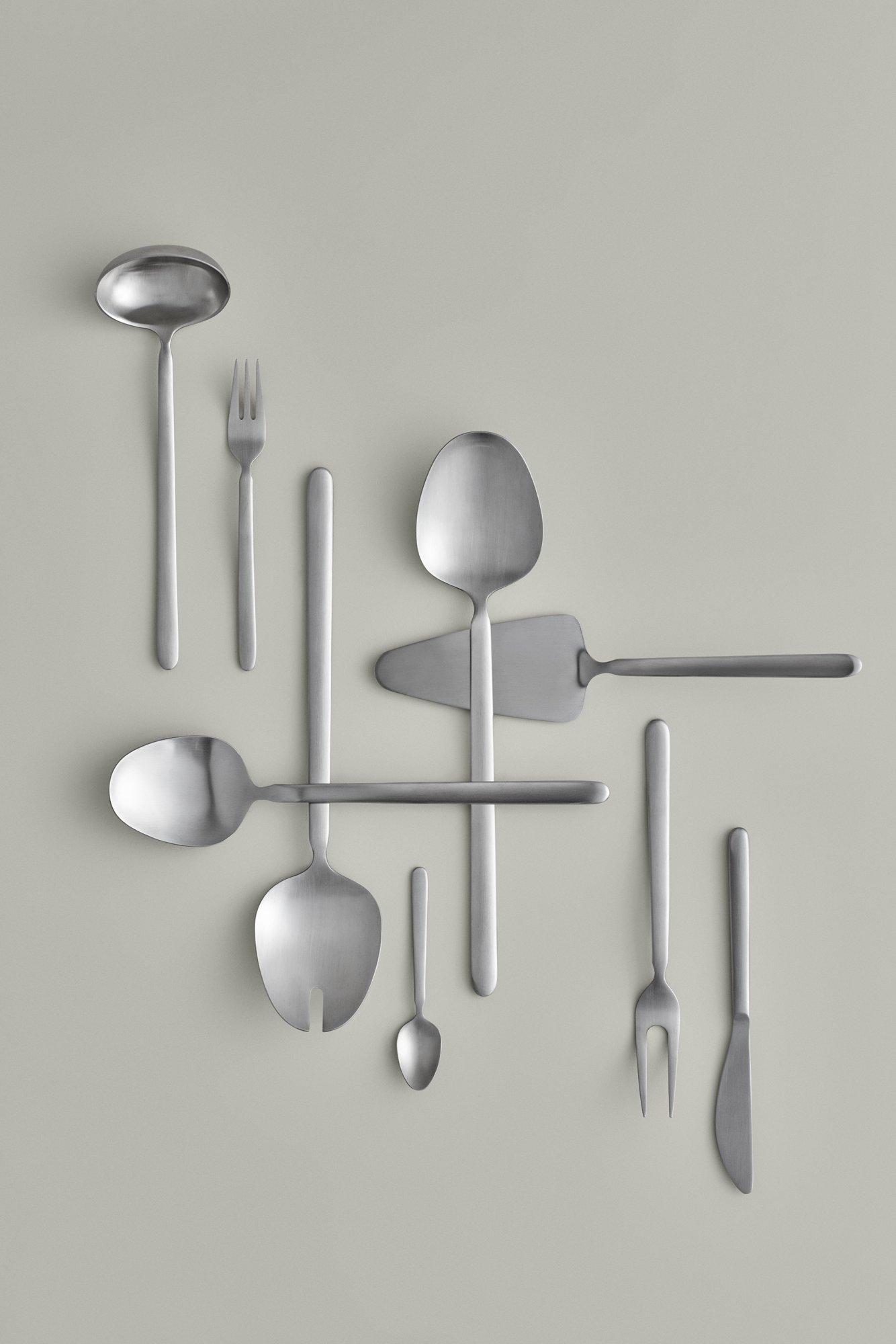 Elegant stainless steel cutlery arranged creatively on a light background.