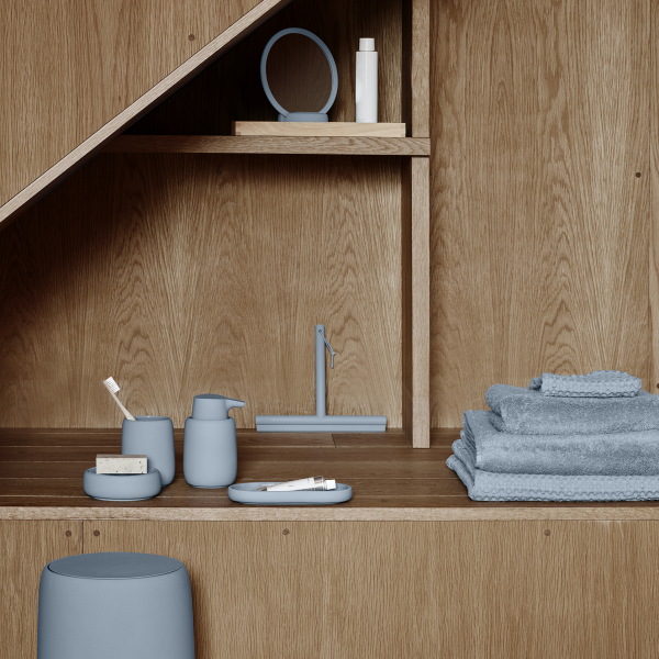 Elegante Badezimmerregalgestaltung mit sanften blauen Accessoires und Holzelementen.