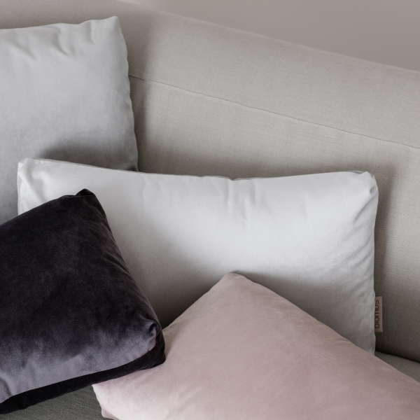 Weiche dekorative Kissen in gedämpften Farben auf einem modernen Sofa angeordnet.