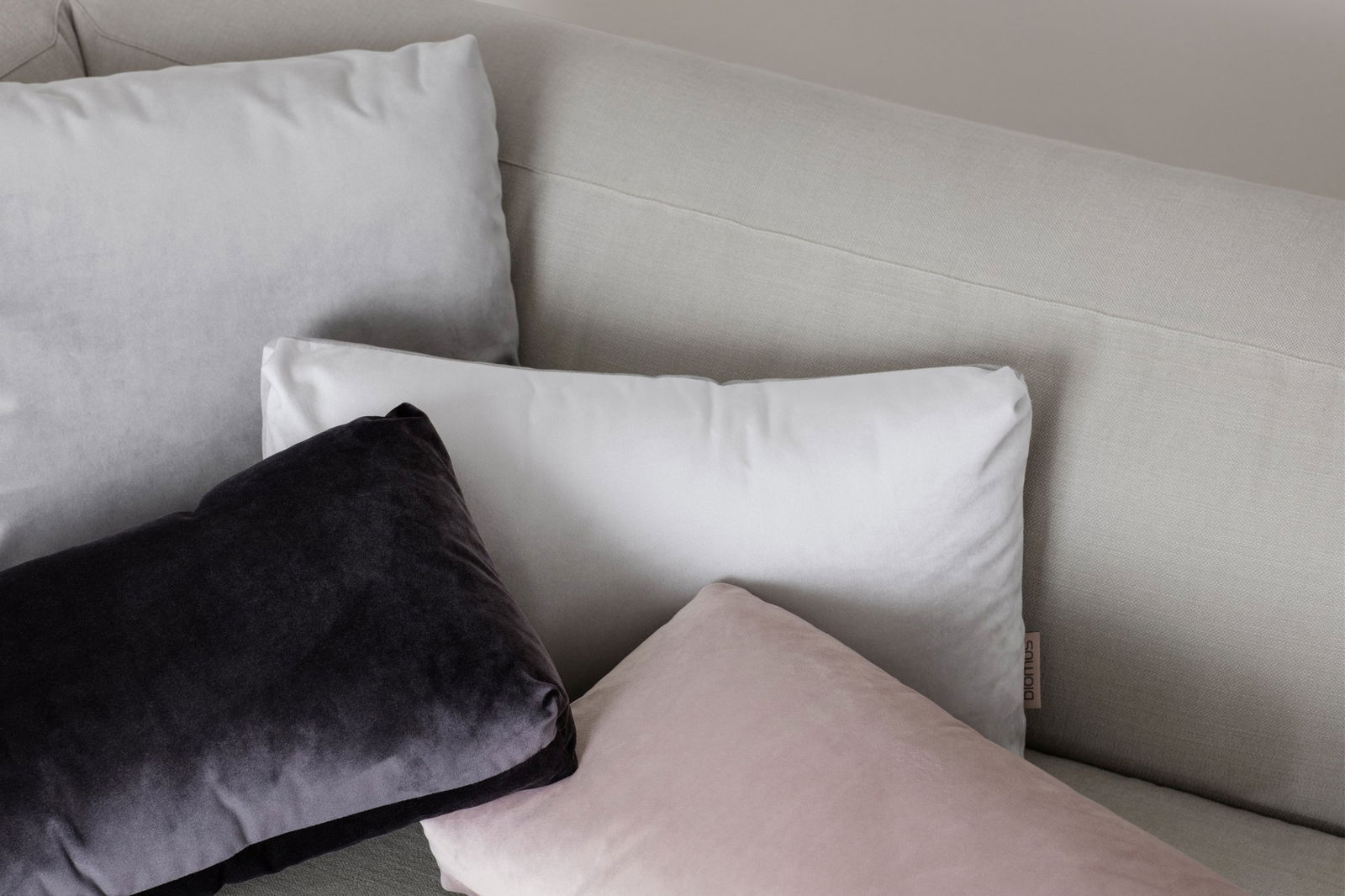 Weiche dekorative Kissen in gedämpften Farben auf einem modernen Sofa angeordnet.