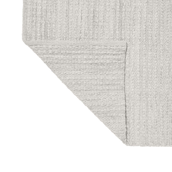 Soft gray woven rug corner with texture details and a clean edge.