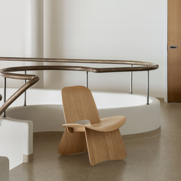 Moderner Holzstuhl in einem stilvollen Interieur mit geschwungenen Geländern und minimalistischem Design.