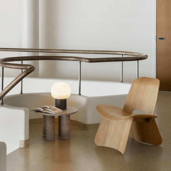 Modernes Interior Design mit einem stilvollen Holzstuhl, einem runden Beistelltisch und ambienter Beleuchtung.