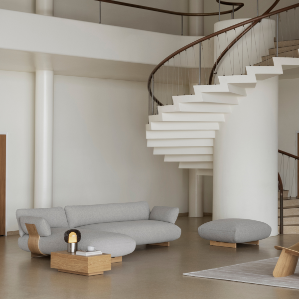 Modernes Wohnzimmer mit einem grauen Sofa, einem einzigartigen Couchtisch und einer eleganten Wendeltreppe.