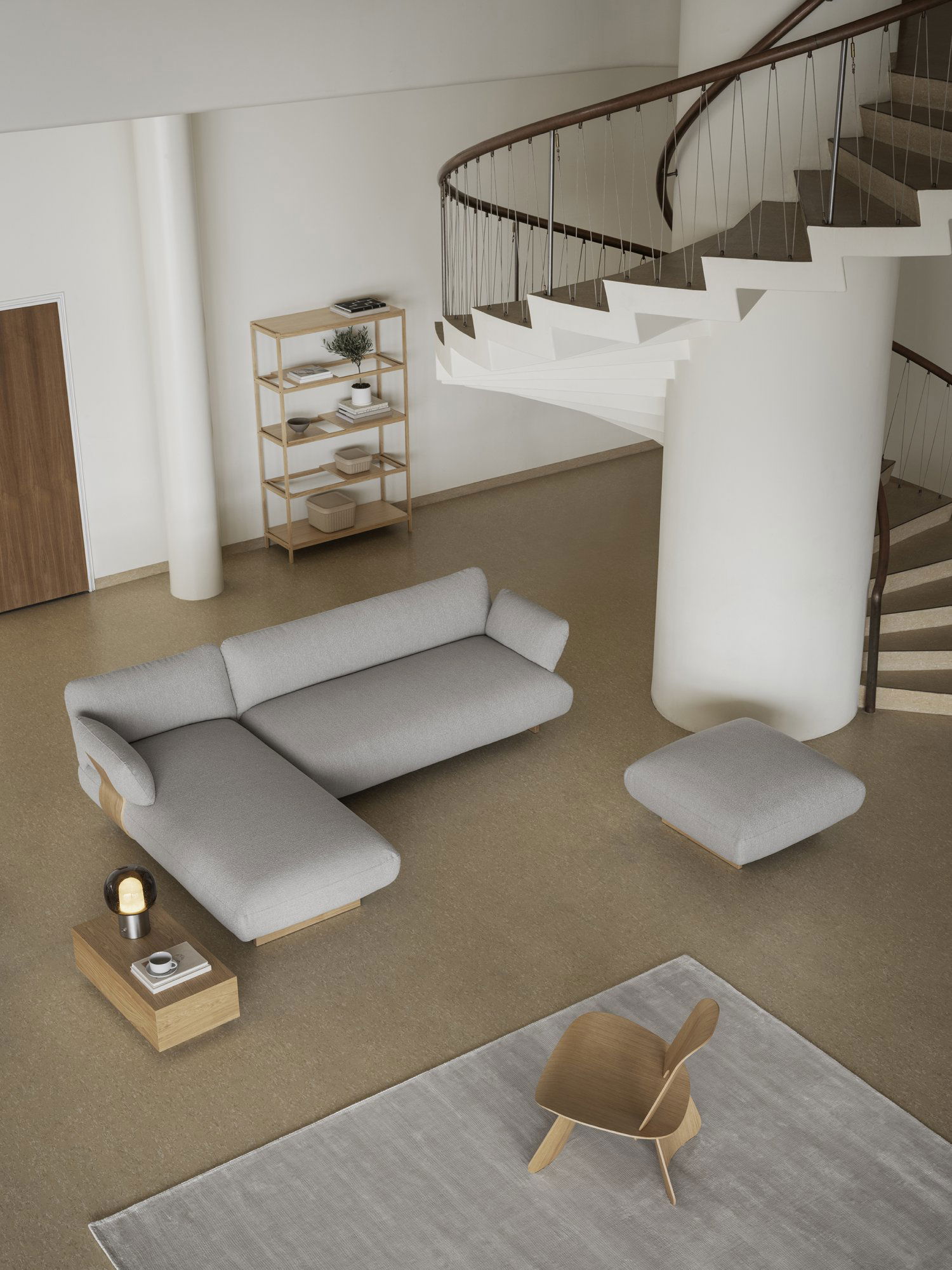 Modernes Wohnzimmer mit einem grauen Ecksofa, minimalistischer Dekoration und einer Wendeltreppe.