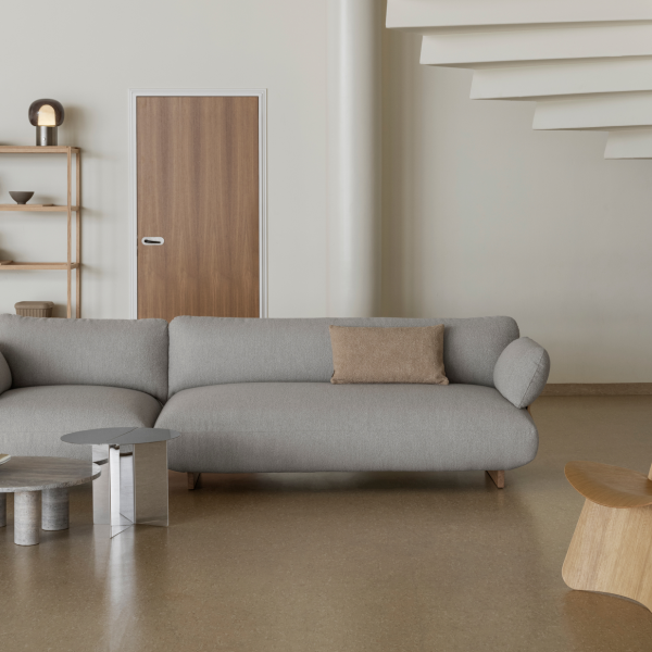 Moderner Wohnraum mit einem grauen Sofa, minimalistischer Dekoration und Holzelementen.