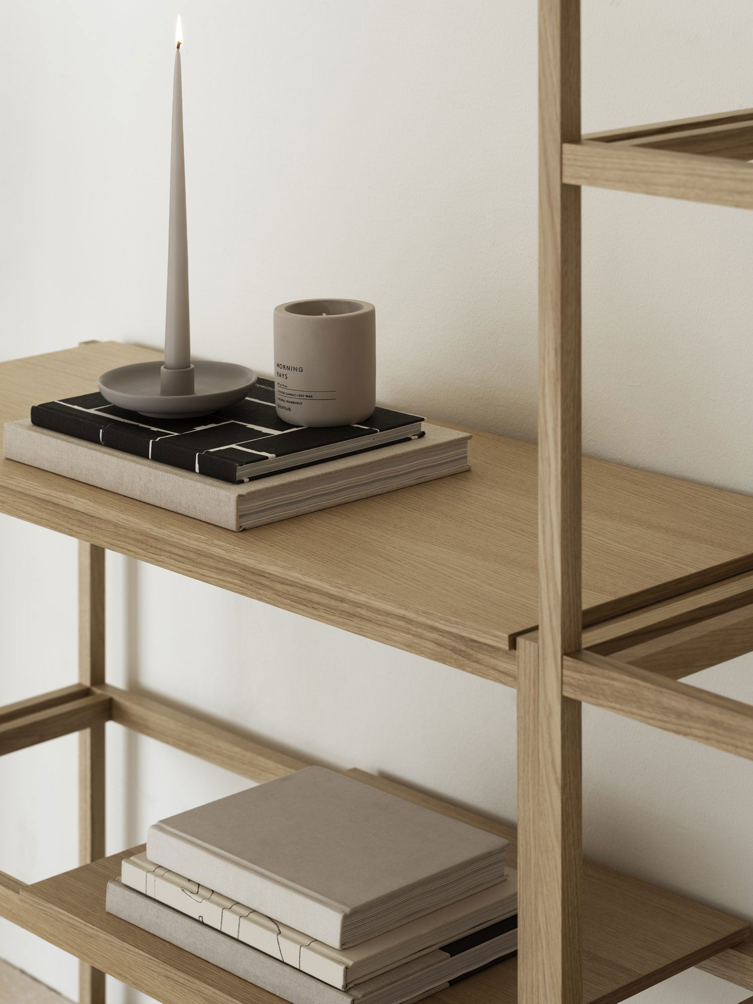 Stylish wooden shelf decor with books, a candle, and a minimalist vase.