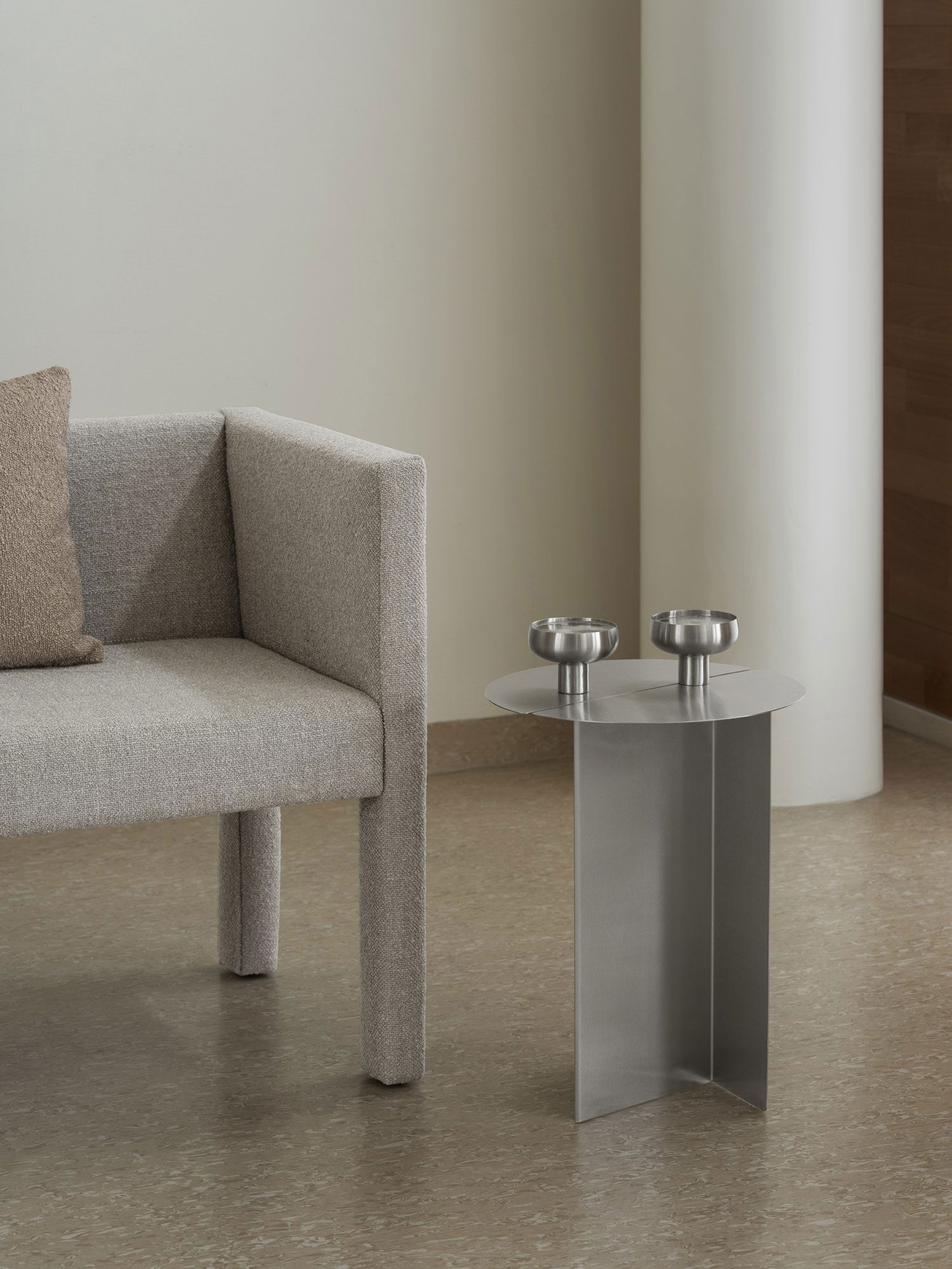 Modern living room with a gray sofa and metallic side table featuring two bowls.